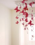 Wnętrze dziennego domu pomocy. Na tle kremowych ścian i okna, ozdoba w postaci ręcznie wykonanych czerwonych motyli zwisających z sufitu.